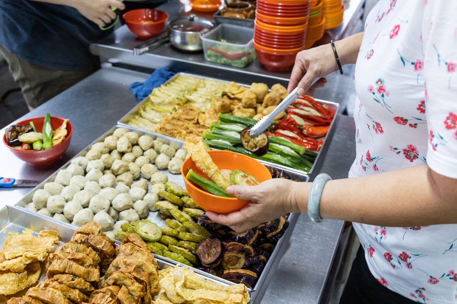 Comida callejera de China. Mujer sazonando vegetalesl